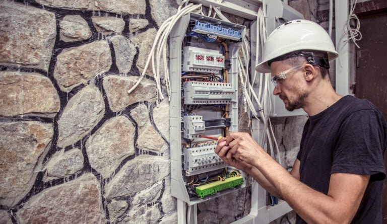 male electrician works switchboard with electrical connecting cab